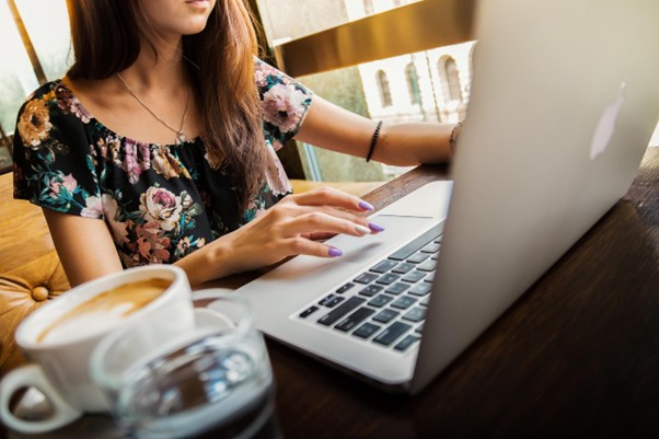 Image showing a woman with a cup of coffee looking at a computer.